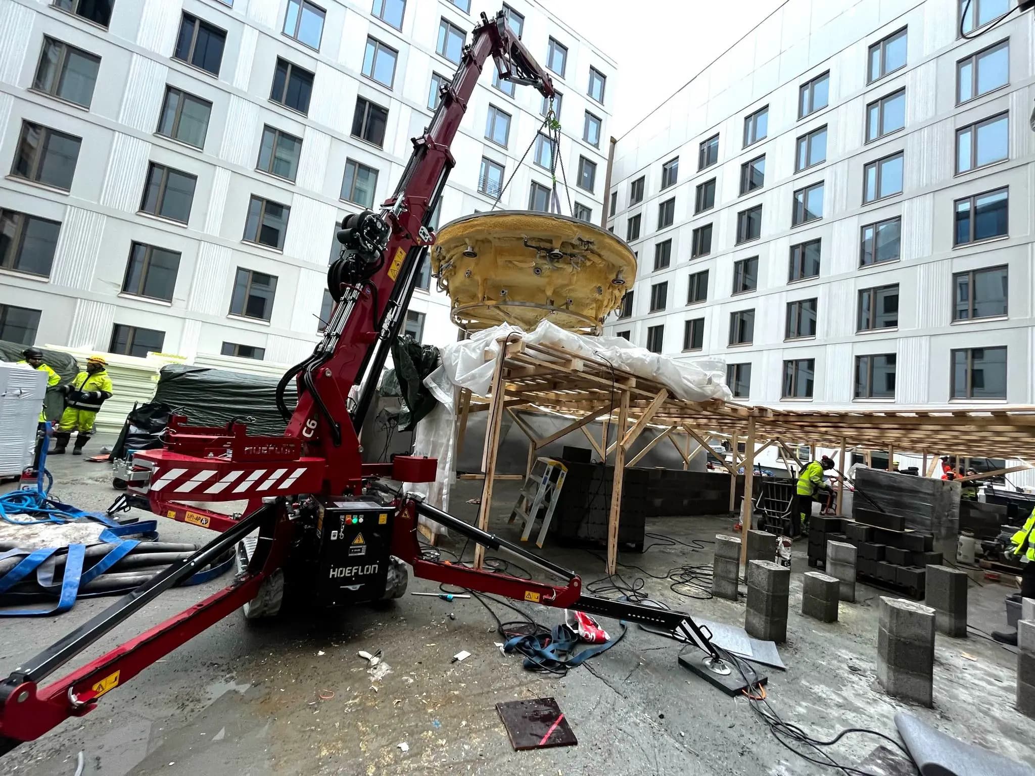 Grue Hoeflon soulevant un objet sur le chantier.