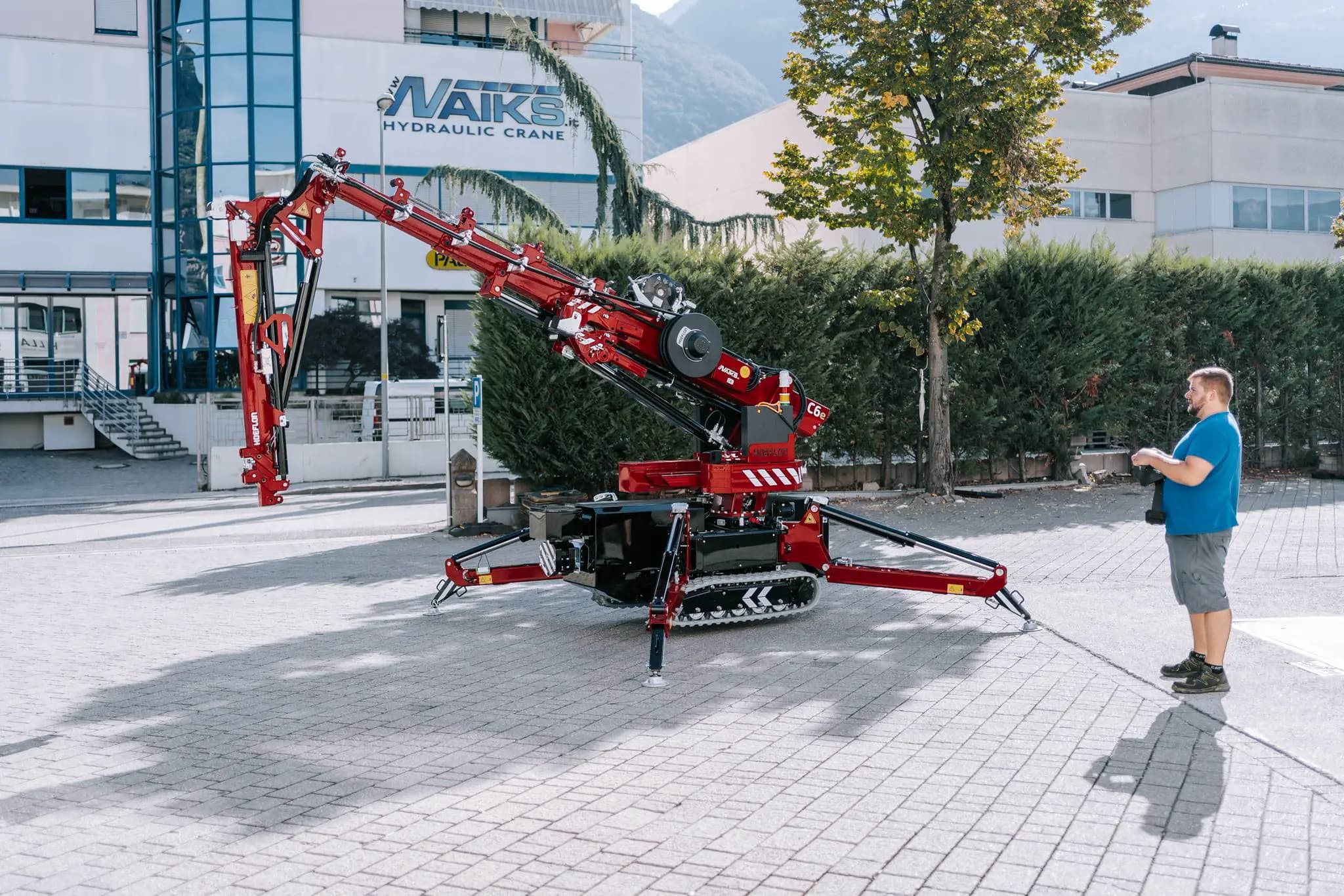 Grue Hoeflon en action dehors, homme contrôle la grue avec panneau à distance.