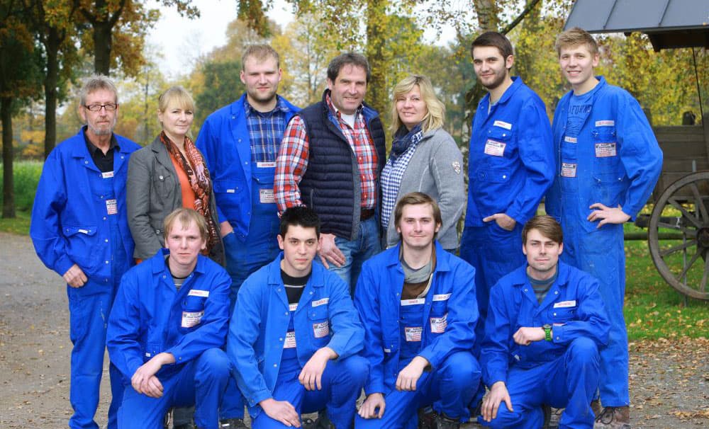 Photo de groupe d'employés en combinaisons bleues, en extérieur dans la nature.