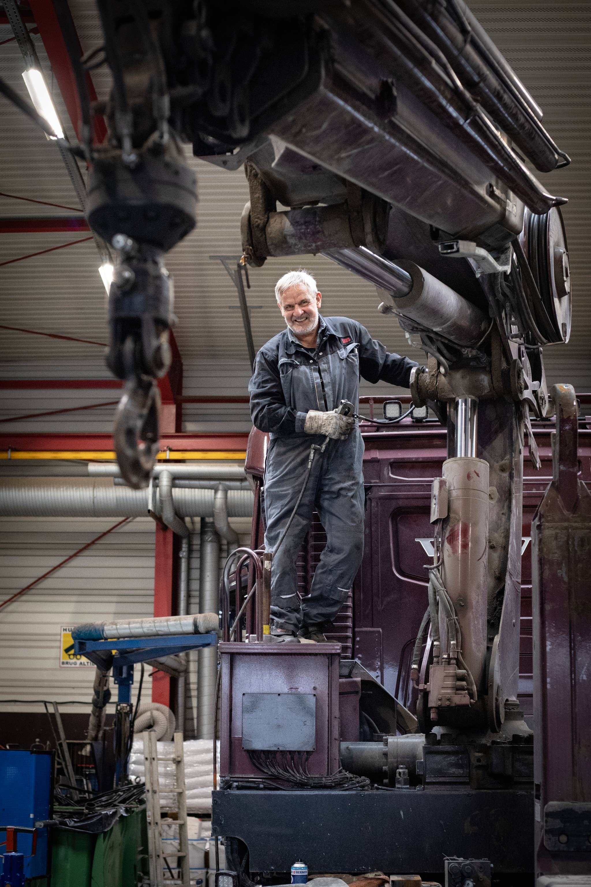 Mécanicien travaillant sur une grue dans un atelier.