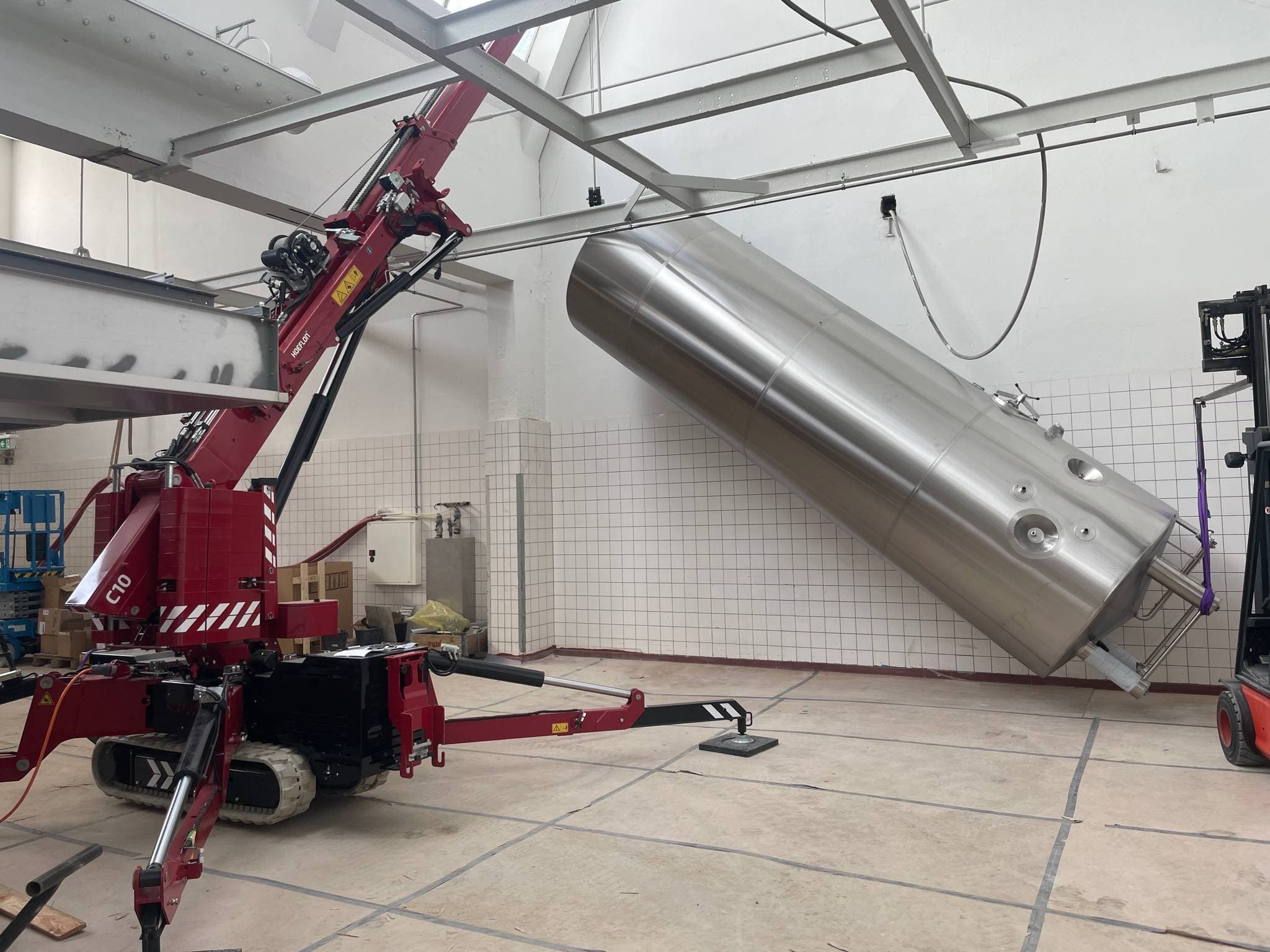 Hoeflon C10 soulevant un grand cylindre dans une halle industrielle.