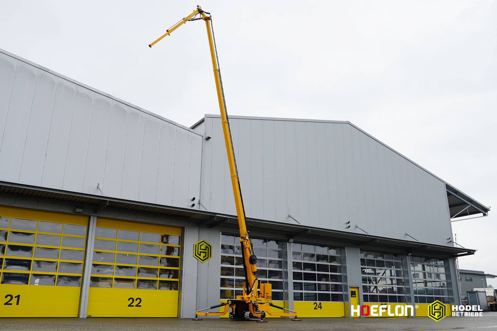 Grue sur chenilles Hoeflon C10e avec flèche haute pour un bâtiment.