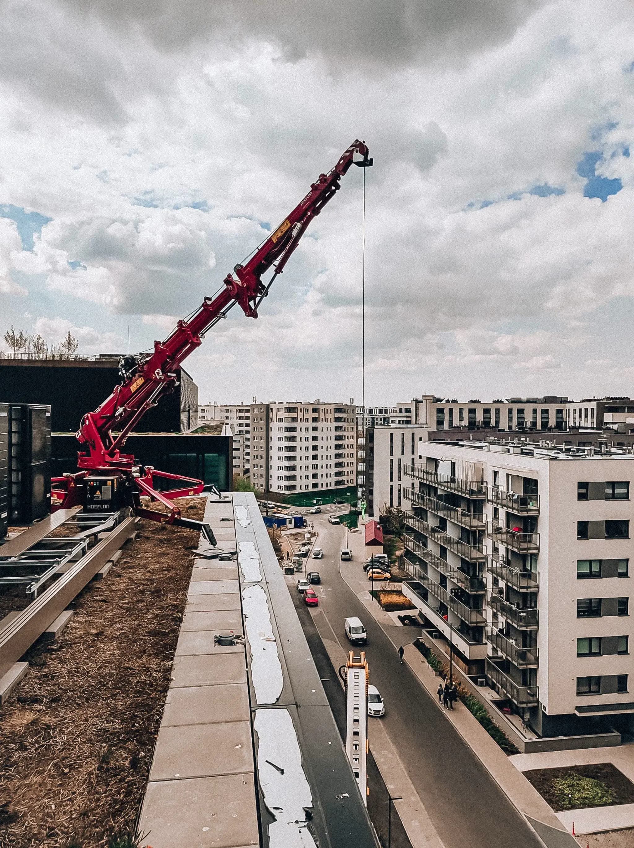 Grue Hoeflon soulevant quelque chose du toit d'un bâtiment.